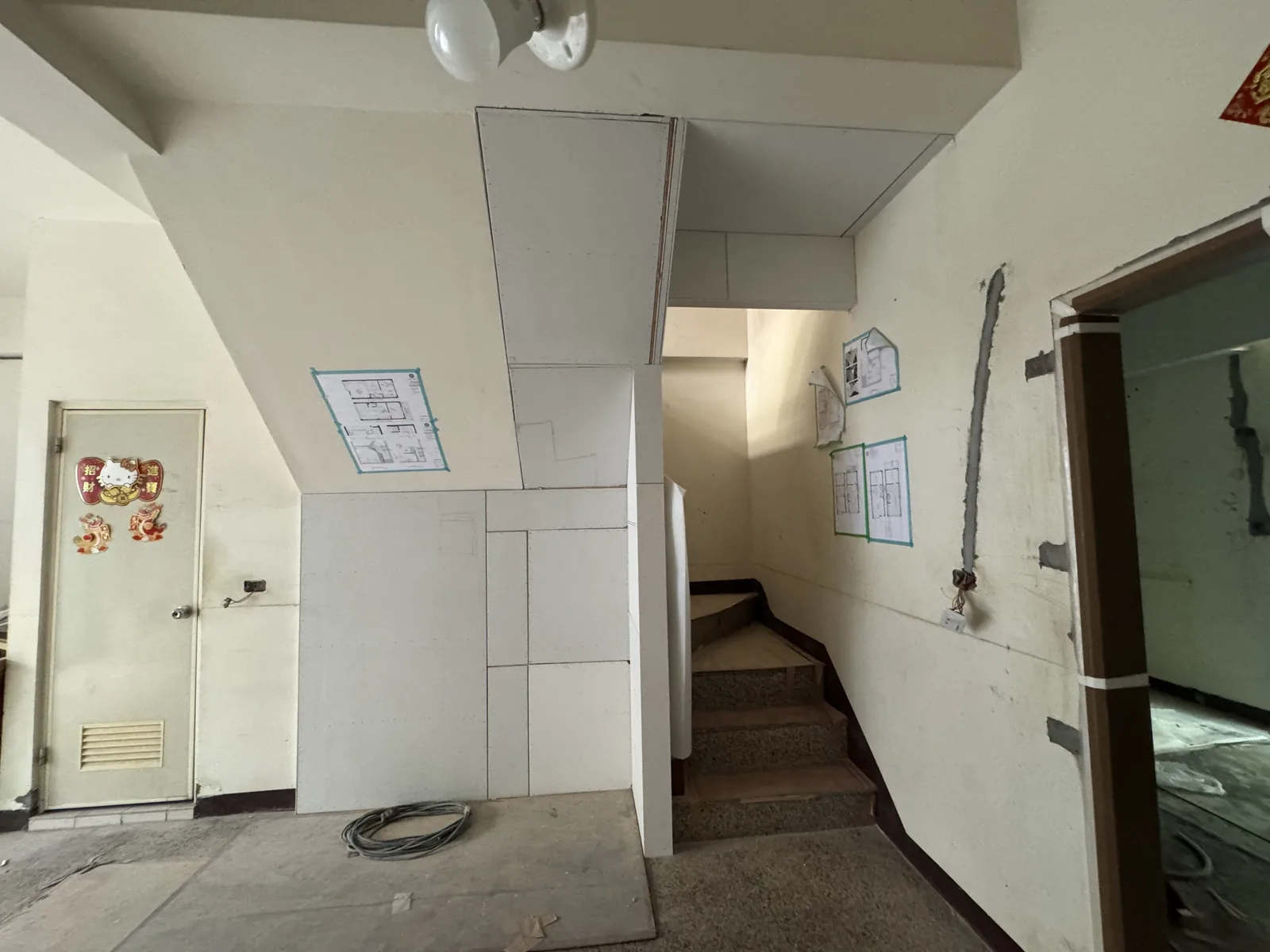 施工中：樓梯口釘上木作隔間，牆上貼著平面圖現場比對